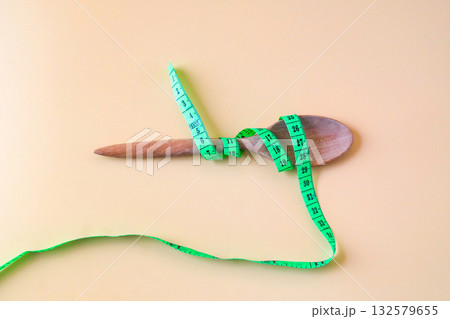 A Measuring tape for tying wood spoon,diet, healthy lifestyle concept. A Measuring tape for tying wood spoon,diet, healthy lifestyle concept. 132579655