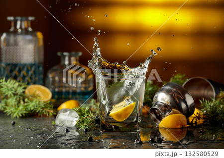 Slice of lemon fall in glass with cocktail, creating beautiful splashes. Slice of lemon fall in glass with cocktail, creating beautiful splashes. 132580529