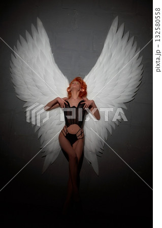 Sexy woman with big white angel wings leaning on the wall Sexy woman with big white angel wings leaning on the wall 132580558