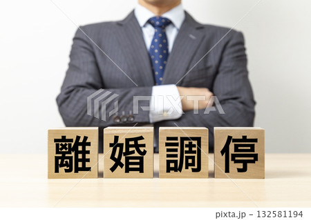 「離婚調停」と書かれたブロックと腕組みをするビジネスマン 132581194