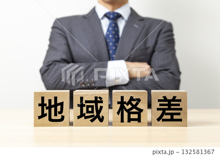 「地域格差」と書かれたブロックと腕組みをするビジネスマン 「地域格差」と書かれたブロックと腕組みをするビジネスマン 132581367