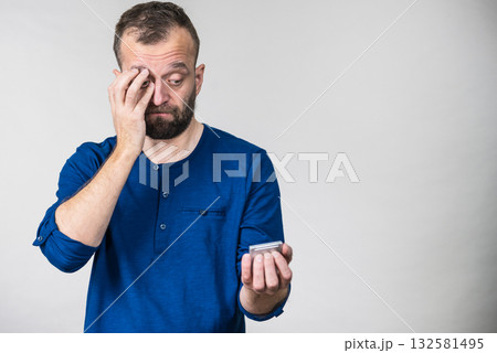 Worried adult man looking at smartphone 132581495