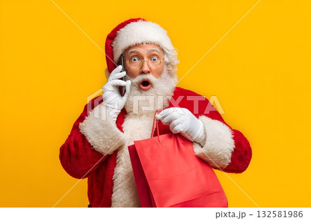 Christmas man talking on phone holding gift bag. 132581986
