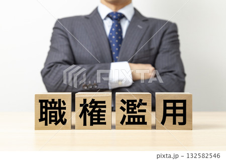 「職権濫用」と書かれたブロックと腕組みをするビジネスマン 「職権濫用」と書かれたブロックと腕組みをするビジネスマン 132582546