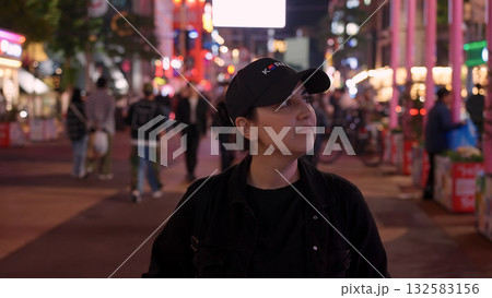 Woman exploring a bustling street in Seoul at night 132583156