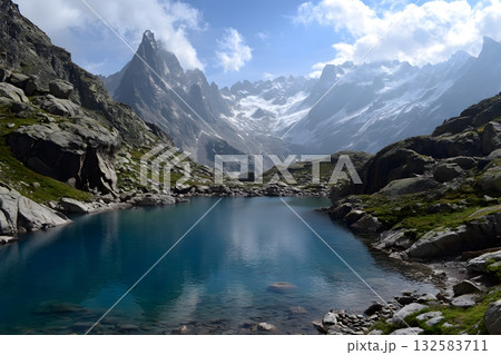 The serene travel landscape shows a blue lake nestled among rocky mountains and snow peaks. 132583711