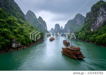 Boats journey through a serene travel landscape of green mountains and water. 132583782