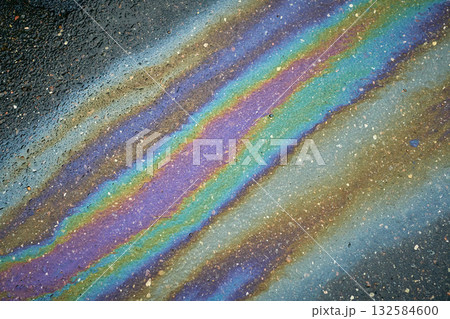 Oil slick creating a colorful abstract pattern on wet asphalt, showing environmental pollution. 132584600