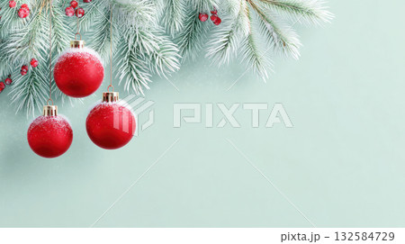 Festive red Christmas ornaments hanging from frosted evergreen branches against a soft mint green background, creating a cheerful holiday atmosphere Festive red Christmas ornaments hanging from frosted evergreen branches against a soft mint green background, creating a cheerful holiday atmosphere 132584729
