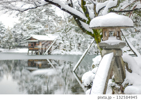 金沢・兼六園の冬、雪を戴く徽軫灯籠と霞ヶ池の水面に映る内橋亭の雪景色 132584945