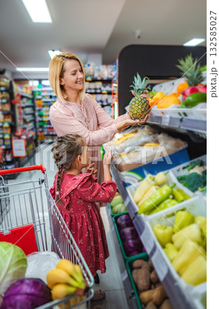 Mother and daughter shopping for fresh fruit in supermarket 132585027