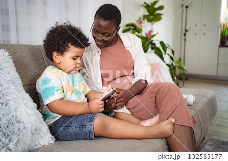 Mother and son using smartphone together on couch 132585177