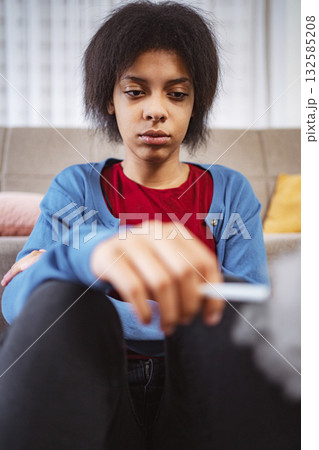 Young woman smoking a cigarette at home looking down 132585208