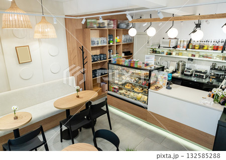 Cozy cafe interior with colorful pastries and drinks on display in a bright setting Cozy cafe interior with colorful pastries and drinks on display in a bright setting 132585288