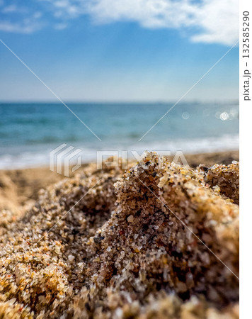 Macro View of Sand Grains on Beach with Sea in Background Macro View of Sand Grains on Beach with Sea in Background 132585290