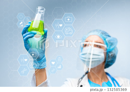 Scientist observes green liquid in flask for research purposes related to health and medicine 132585369