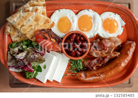 Delightful breakfast platter featuring eggs, sausage, and fresh vegetables Delightful breakfast platter featuring eggs, sausage, and fresh vegetables 132585485