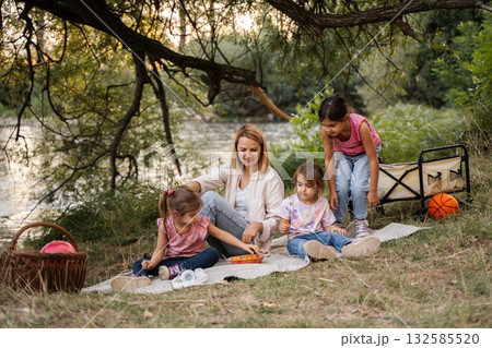 Family enjoying a summer picnic by the river Family enjoying a summer picnic by the river 132585520