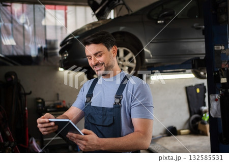Mechanic Smiling and Using Digital Tablet in Auto Repair Shop 132585531