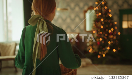 Back view of girl carrying ornament basket toward Christmas tree. Warm family tradition scene. Soft bokeh background with copy space for holiday marketing. Christmas background Back view of girl carrying ornament basket toward Christmas tree. Warm family tradition scene. Soft bokeh background with copy space for holiday marketing. Christmas background 132585867