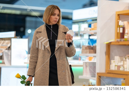 A woman holding a white cosmetic product and a yellow rose A woman holding a white cosmetic product and a yellow rose 132586341