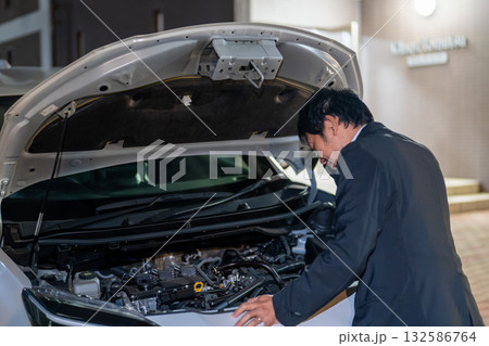 夜の路上で車の不具合を確認。車のボンネットを開けてお手上げのスーツの男性。 夜の路上で車の不具合を確認。車のボンネットを開けてお手上げのスーツの男性。 132586764