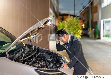 夜の路上で車の不具合を確認。車のボンネットを開けてお手上げのスーツの男性。 132586766