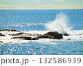 きらめく水面と岩礁で砕け散る波 132586939