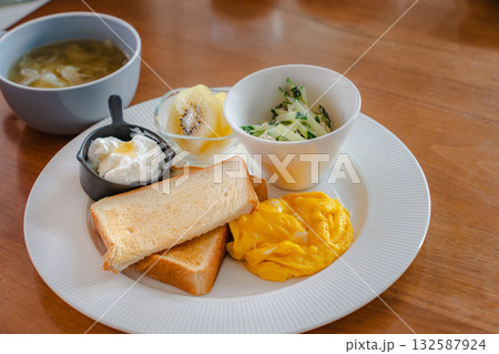スクランブルエッグとトースト、スープとフルーツを添えた洋風朝食 132587924