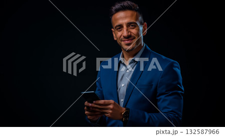 A man in a blue suit holding a cell phone 132587966
