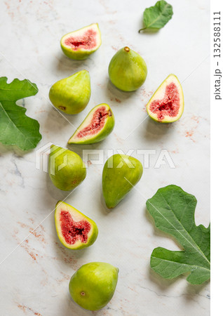 Flat lay of sweet green figs, sliced and leaves on a light marble background. Flat lay of sweet green figs, sliced and leaves on a light marble background. 132588111