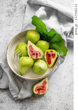 Sweet green figs in a plate with leaves and napkin on a gray concrete background. Sweet green figs in a plate with leaves and napkin on a gray concrete background. 132588112