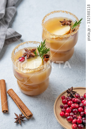 Two glasses of hot apple cider with cinnamon, anise, brown sugar and rosemary on a light background 132588118