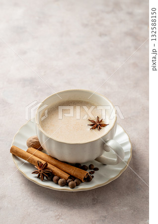 Traditional Indian masala chai tea with milk and spices in a white cup on a light background. Traditional Indian masala chai tea with milk and spices in a white cup on a light background. 132588150