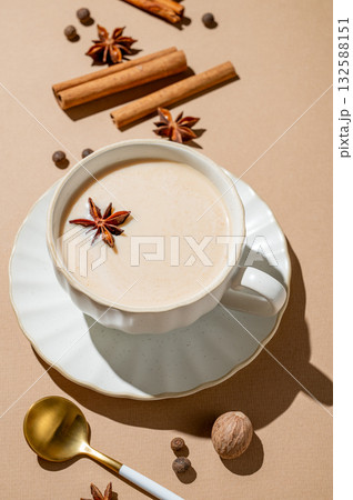 Traditional Indian masala chai tea with milk and spices in a cup on a beige background with cinnamon 132588151