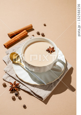 Traditional Indian masala chai tea with milk and spices in a cup on a beige background 132588156