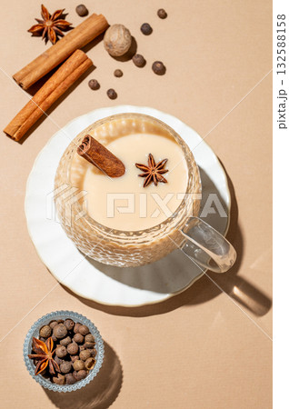 Traditional Indian masala chai tea with milk and spices in a cup on a beige background 132588158
