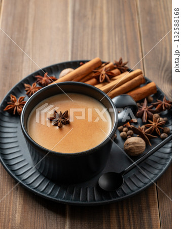 Traditional Indian masala chai tea with milk and spices in a black cup  on a wooden background 132588168