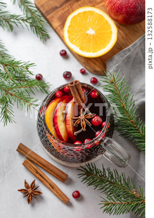 A cup of red mulled wine with spices, orange and apple slices on a light background 132588173