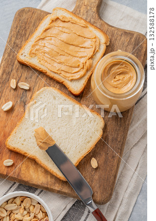 Peanut butter toast on a wooden board on a light background with scattered nuts and knife. 132588178