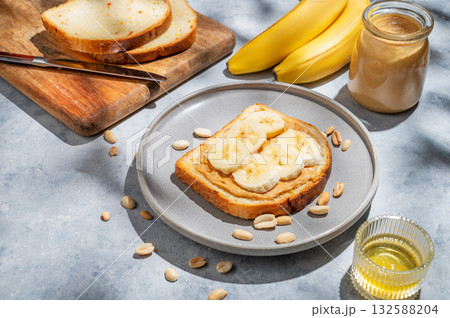 Peanut butter toast with banana on a plate on a blue background with spread, bread, fruit, honey Peanut butter toast with banana on a plate on a blue background with spread, bread, fruit, honey 132588204