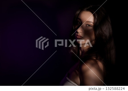 Young woman posing in studio with projected shadows on her face Young woman posing in studio with projected shadows on her face 132588224