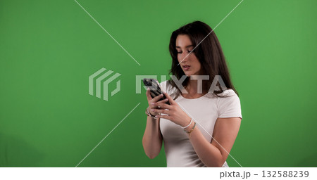 Young woman using smartphone on green screen background 132588239