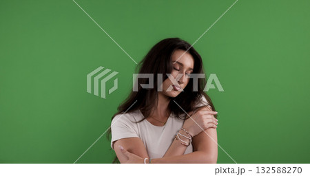 Young woman hugging herself on green background feeling insecure and lonely 132588270
