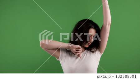 Young woman dancing with arms raised on green screen background 132588301