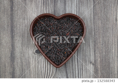pile of black rice in a wooden bowl on a wooden table close-up pile of black rice in a wooden bowl on a wooden table close-up 132588343