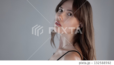 Beautiful model posing and looking over shoulder on gray background 132588592