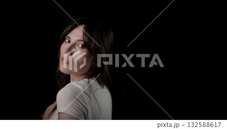Young woman turning her head and looking back over her shoulder Young woman turning her head and looking back over her shoulder 132588617