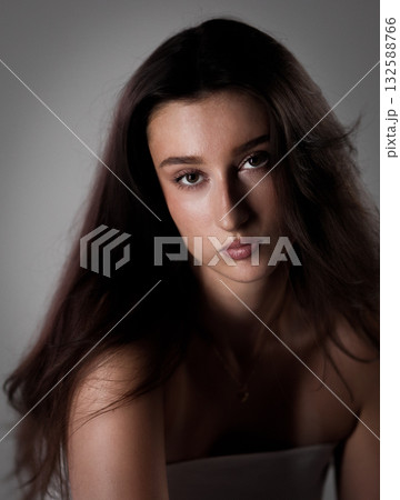 Portrait of a serious young woman with long brown hair posing in studio 132588766