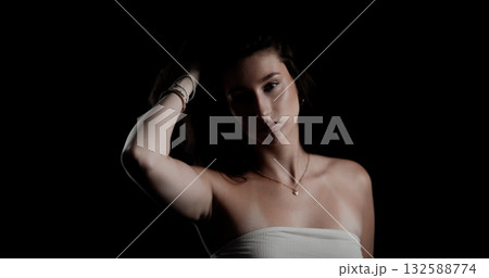 Young woman touching her hair with hand on black background Young woman touching her hair with hand on black background 132588774